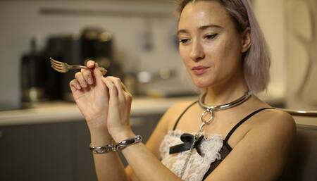 Sofi_ dressed as a maid reads a novel in handcuffs