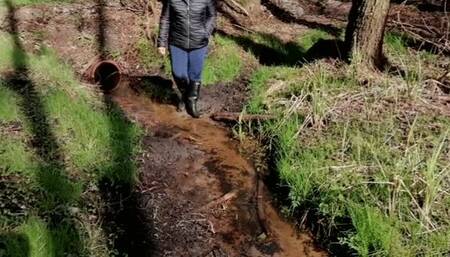 Black rubber boots and a stream in the forest