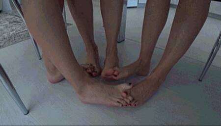 3 girls barefoot sitting at a table interlocking their toes c