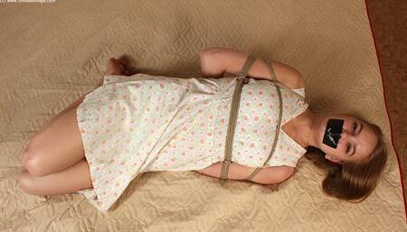 Irene: tapegagged barefoot girl, wearing old-fashioned dress, hogtied with hemp rope, is wiggling on a mattress, trying to loosen her bonds (HD MOV)