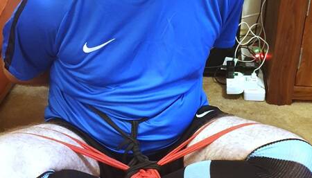 Man in football kit bound and gagged cross-legged by woman 1