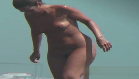 Sexy toned body walking naked on a crowded beach