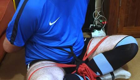 Man in football kit bound and gagged cross-legged by woman 3