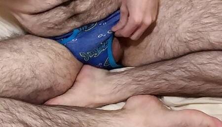 Skinny hairy white guy laying on the bed teases bushy pubic hair in small blue undies until the camera falls down