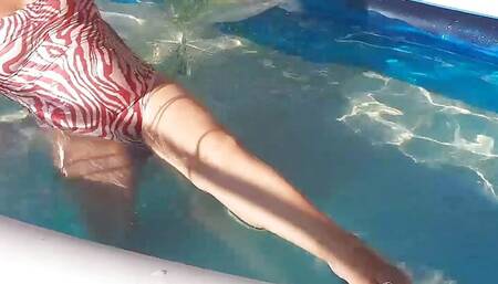 Elegant and flexible babe, swimming underwater in the outdoor swimming pool. SWIMMINGSUITE