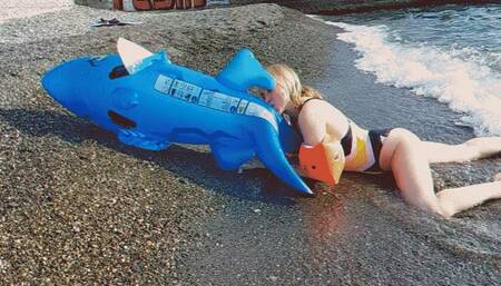 Alla inflates a blue inflatable shark with her mouth on the beach!!!