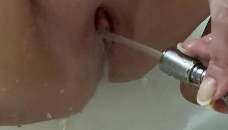 The whore jerks off her clitoris and cunt with her shower.