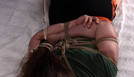 Marlene: barefoot girl, wearing green t-shirt and sport shorts, hogtied with her foot tightly tied to her hair tie, wiggles on the bed, unable to turn to her side (HD MP4)