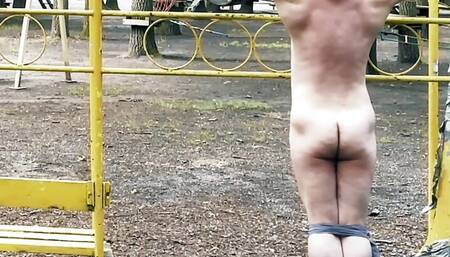 Crucified naked, tied and helpless guy in public park