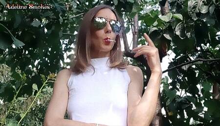 Smoking a cigarette outdoors with sunglasses on