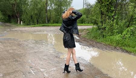 a girl in high-heeled leather boots walks through huge mud puddles in which her boots begin to sink