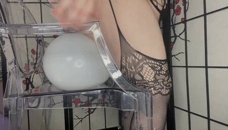 BBW balloon sitting pop on clear chair, from the side and below