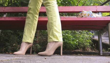 Raven dangling her high heels crossing legs while sitting on a bench outdoor