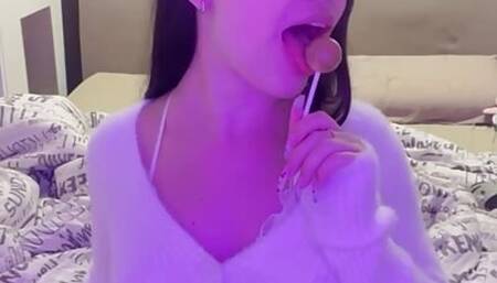 This busty lustful bitch sucks candy on the bed and dreams of a big dick