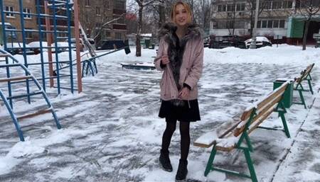 girl having fun on the playground in a summer dress and tights in the snowI