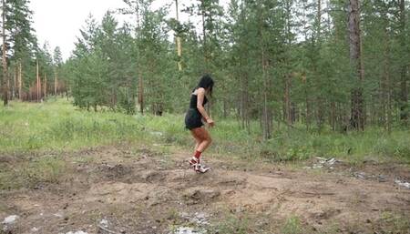 Hot girl in high-heeled boots smoking and walking on sand and falling through sand