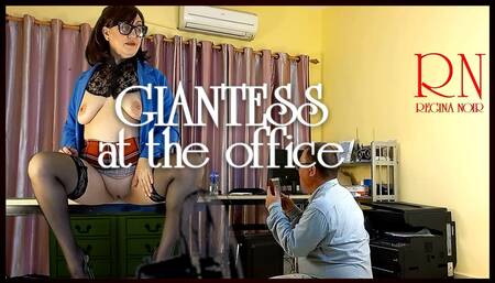 A giant secretary sits on an office desk. The manager guy is very surprised at her height.