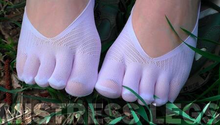 Goddess Feet in cute white socks with jeans on the spring grass field