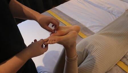 Ticking Chinese girl’s beautiful feet on bed
