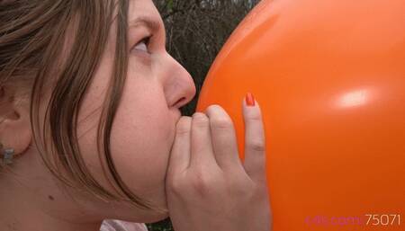 Simona inflates a giant orange balloon outside (FULLHD quality)