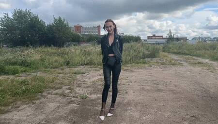 A girl in leather pants and a jacket put on high-heeled shoes with rhinestones, she does not like that they do not match her outfit, so she decides to stain them with thick black dirt so that not a single pink sparkle is on her shoes