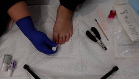 Pedicure and painting toenails while wearing surgical gloves