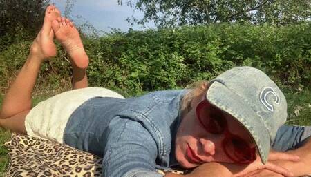 Lola rubbing her bare soles in the park