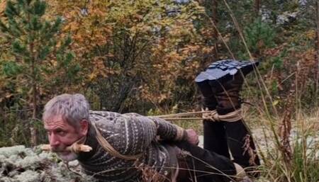 Man in boots hogtied in the woods