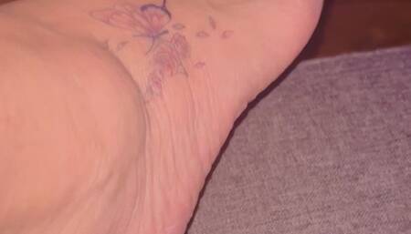 Magnifique pieds feet sensuel se caressant la cuisse avec ongles vernis rouge et tatouage