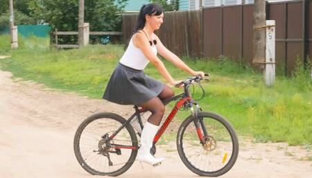 Pretty girl in high heels riding a bike and watering flowers