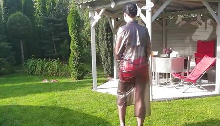 Garden, beautiful sunny day. Wanilianna in transparent raincoat, black seamed nylons