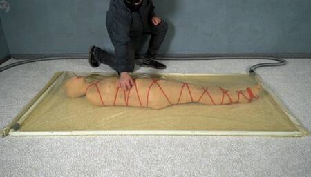 Mummification with bandages and rope bondage with ankle brace in a vacuum bed
