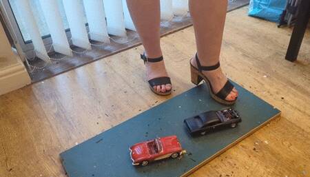 Giantess Lou crushes two old model cars Chevy corvette & Chevy Malibu in big heels high left view