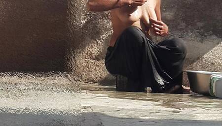 Indian sister-in-law is bathing in the open courtyard of the house, putting a finger in her burrow and rubbing the body, sister-in-law is washing the bathroom.