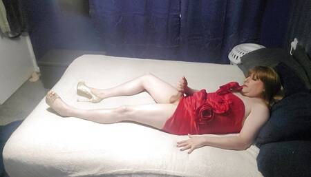 crossdresses layed on bed in little red dress